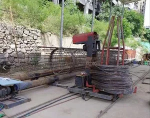 Rebar cage winding machine on site: roller carriers turning a spiral rebar cage
